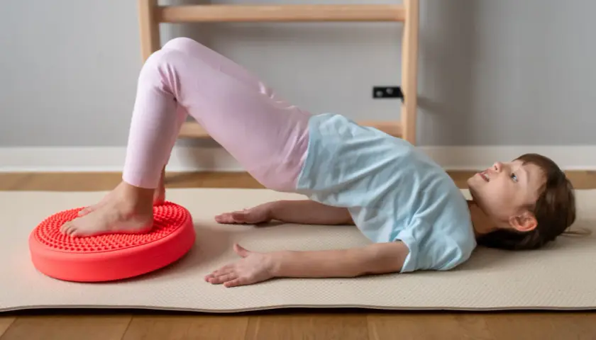 Dziecko ćwiczy na poduszce sensorycznej dla dzieci z ADHD, poprawiając równowagę i koordynację.