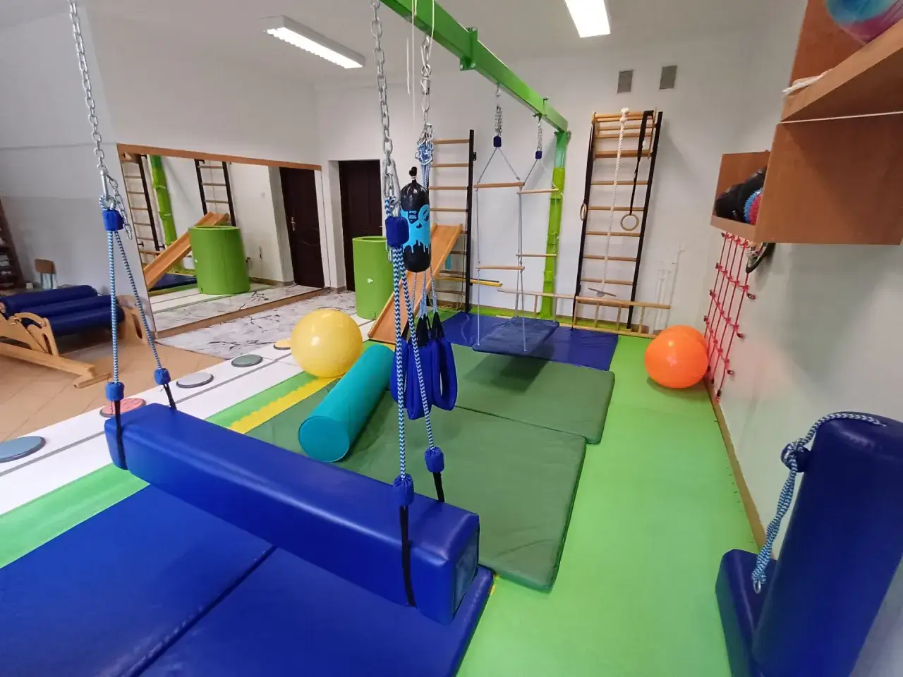 sala do terapii integracji sensorycznej, dziecko na huśtawce terapeutycznej, sprzęt do terapii SI